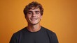 © AdorStudios - young stylish man in a black t-shirt smiling and standing in front of an orange background, portrait photography of a confident male model with a trendy outfit and charming expression in a studio sett