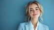 © AdorStudios - confident young businesswoman in an elegant light blue suit and white shirt, posing in a studio with a blue background, looking to the side with a cheerful smile