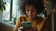 © AlfaSmart - Young female using smartphone indoors in cozy living room environment