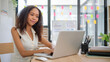 © wattana - Smiling African American businesswoman working with laptop at modern workplace.