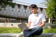 © wattana - Student enjoying remote work or study in an open campus surrounded by greenery. Education concept.