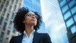 © Soklin - A professional businesswoman standing in front of a tall office building, looking up confidently.
