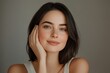© Papisut - Happy young woman with sleek hair touching her face radiant skin soft beauty lighting positive and confident expression neutral background