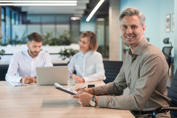 Wall Mural - Businessman with his staff, people group in background at modern bright office indoors.