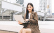 © dodotone - Beautiful business freelance adult asian woman using laptop sitting at outdoor on day