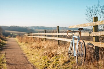 Poster - Bicycle resting by a wooden fence on a sunny day in a peaceful countryside setting. Generative AI