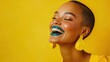 © vadosloginov - Vibrant portrait of a young woman smiling brightly against a bold yellow backdrop showcasing colorful makeup and accessories