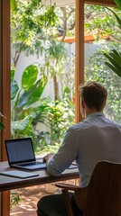 Aufkleber - Relaxed man working at a minimalist desk surrounded by greenery in a tranquil indoor setting