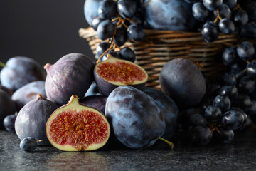 Poster - Blue grapes, blue plums, and figs on a black stone table.