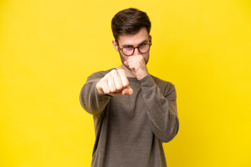 Wall Mural - Young caucasian man isolated on yellow background with fighting gesture