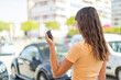 © luismolinero - Young woman holding car keys at outdoors in back position