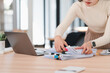 © kenchiro168 - Organized asian woman sorting paperwork at desk with laptop, showcasing productivity and focus.
