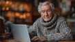 © Vancouver - Elderly caucasian male working on laptop in cozy sweater at home