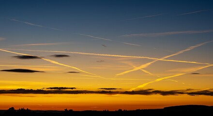 Sticker - Vibrant sunset with contrails and silhouetted landscape under a dramatic sky