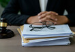 © Anna - A stack of immigration documents resting on a lawyer's desk, with a judge's gavel and reading glasses beside them.