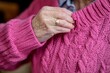 © mohdfaizal - Close-up of Hand Adjusting Cozy Pink Sweater with Cable Knit Design