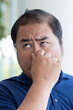 © 9nong - Middle aged olf Asian man covering nose to prevent bad stinking smell, stinking odor, rotten smell with disgusting expression or reaction