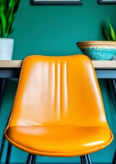 Canvas Print - Close up view of orange chair set in a teal room with plants and wooden table. The lighting is bright and natural. A simple interior design element