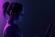 © Anjali - A woman wearing headphones, illuminated by vibrant purple and blue light, uses a laptop.