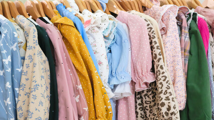 Poster - A rack of clothes with a variety of colors and patterns. The clothes are hanging on a rack, and there are many different types of clothing, including shirts, dresses, and jackets