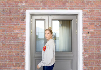 Wall Mural - Young woman opening  the door of the house