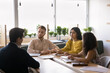 © fizkes - Problem solving workshop. Small group multiethnic diverse students attendees listen to young male professor in formal suit sitting at table in seminar room interact with teacher tutor on consultation
