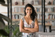© fizkes - Comfort and confidence. Portrait happy smiling beautiful young girl in casual dress student freelancer small business owner stand with arms crossed at cozy home office library bookstore look at camera