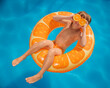 © Sunny studio - Happy child on an inflatable ring holds orange halves like sunglasses. Funny kid is relaxing in the swimming pool on summer vacation