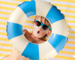 © Sunny studio - Top view portrait of happy child lying on beach towel on summer vacation