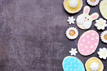 Wall Mural - Easter or spring themed baking side border with assorted cookies and sweet desserts. Overhead view on a dark stone background with copy space.