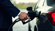 © Kateryna - A man in a suit manages his car with gasoline at the gas station, hand and black refuelling gun close up