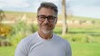 © nyul - Mature rancher wearing glasses and white t-shirt, smiling confidently in rural landscape, enjoying the tranquility of country life. Outdoor portrait of mid adult man in 50s with gray hair.