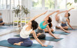 © JackF - Adult woman doing yoga on mat in group in fitness studio