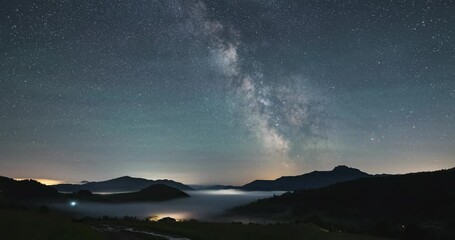 Wall Mural - milky way galaxy stars moving fast over foggy countryside nature, night to day time lapse