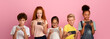 © Prostock-studio - Happy schoolchildren playing mobile games on their phones against pink background