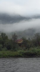 Wall Mural - Vertical video of Tourist recreation center on the bank of the Ursul River early in the morning. Fog is floating over the slopes of mountains.