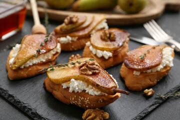 Wall Mural - Board of pear bruschetta with ricotta cheese, walnuts and thyme on black background