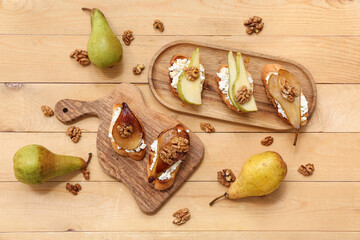 Canvas Print - Boards of pear bruschetta with ricotta cheese and walnuts on wooden background