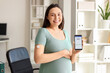 © Pixel-Shot - Young pregnant businesswoman with glucose sensor and mobile phone in office. Gestational diabetes concept