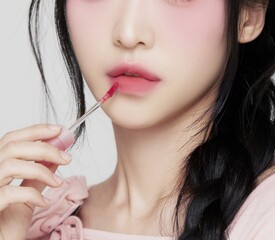 Wall Mural - Portrait of beautiful Asian woman in her 30s with makeup, smooth glowing skin and red lipstick with soft black hair applying lipstick 