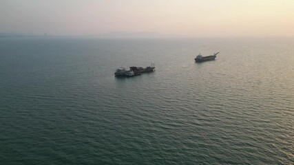 Wall Mural - Drone tranquil maritime scene featuring two ships in distance under a misty sky at sunset