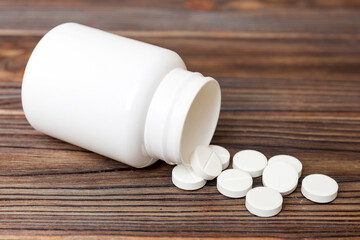 different drugs and health supplement pills poured from a medicine bottle health care and medical top view on colored background