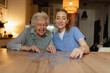 © Halfpoint - Friendly caregiver and elderly patient working on puzzle together, having fun.