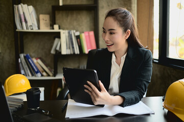 A beautiful, successful Asian female engineer boss working at her desk.