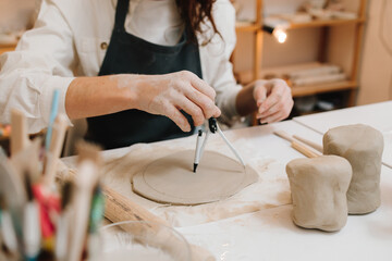 Poster - Artisan with compass shapes and refines a ceramic piece with precision. Potter works on a clay slab with compass.
