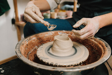 Poster - Potter sculpts a ceramic mug from clay in the pottery studio. Molding earthenware with potters tools.