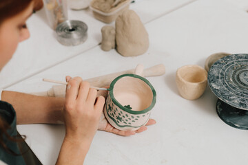 Poster - Design earthenware cup with a traditional pattern. Artist is making decoration on the clay ceramic mug after oven firing.