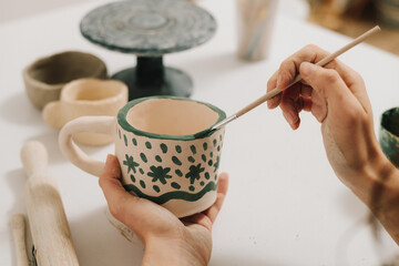 Poster - Design earthenware cup with a traditional pattern. Artist is making decoration on the clay ceramic mug after oven firing.