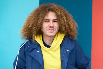 Smiling young man with curly hair posing outdoors