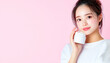 © bcendet - Young woman presenting beauty product with pink background, promoting skincare